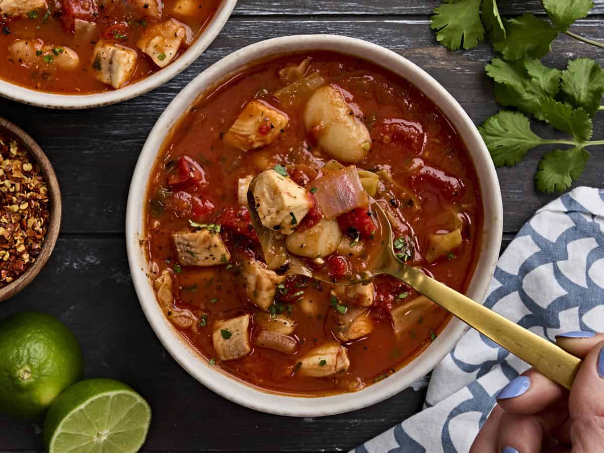 Vista superior de un tazón de sopa de pescado, con una cuchara tomando un poco.