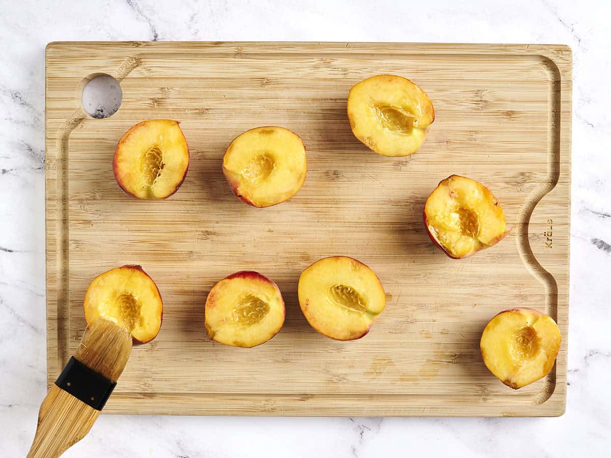 Un cepillo de cepillado de durazno a las mitades con aceite.