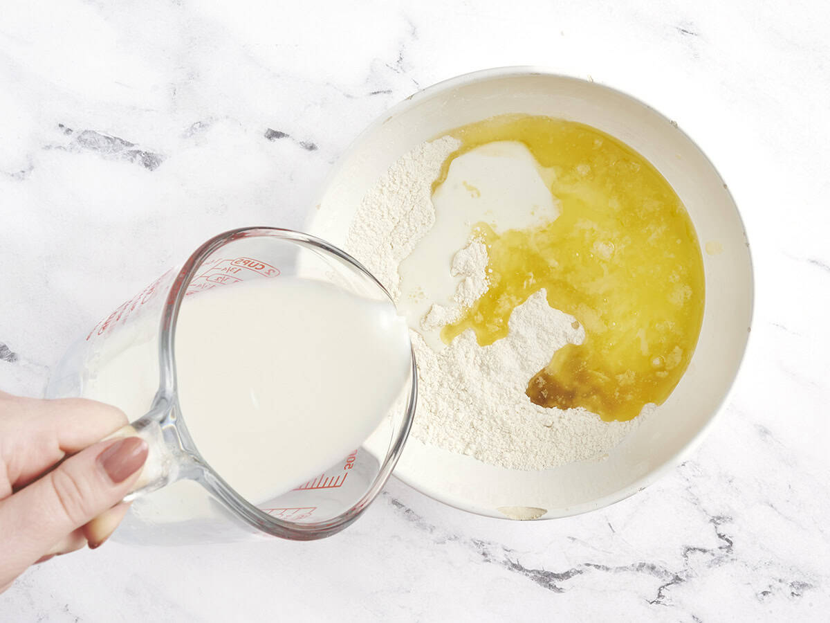 La leche y la mantequilla derretida se verten en los ingredientes secos para el zapatero de durazno.