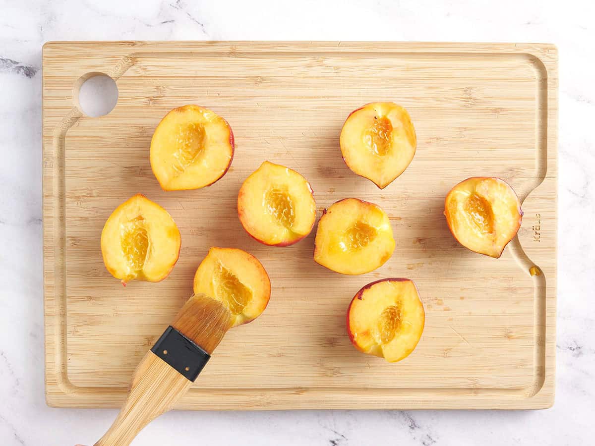 Las mitades de durazno se cepillan con aceite.