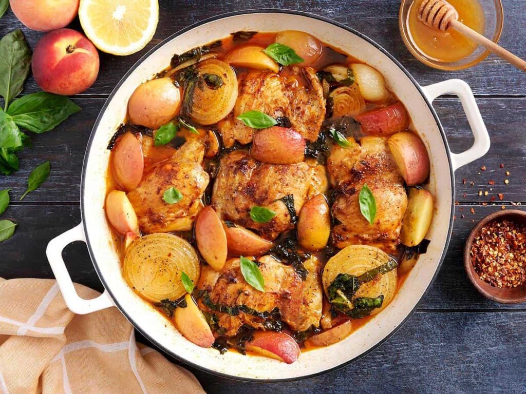 Overhead view of savory braised peach chicken in a skillet.