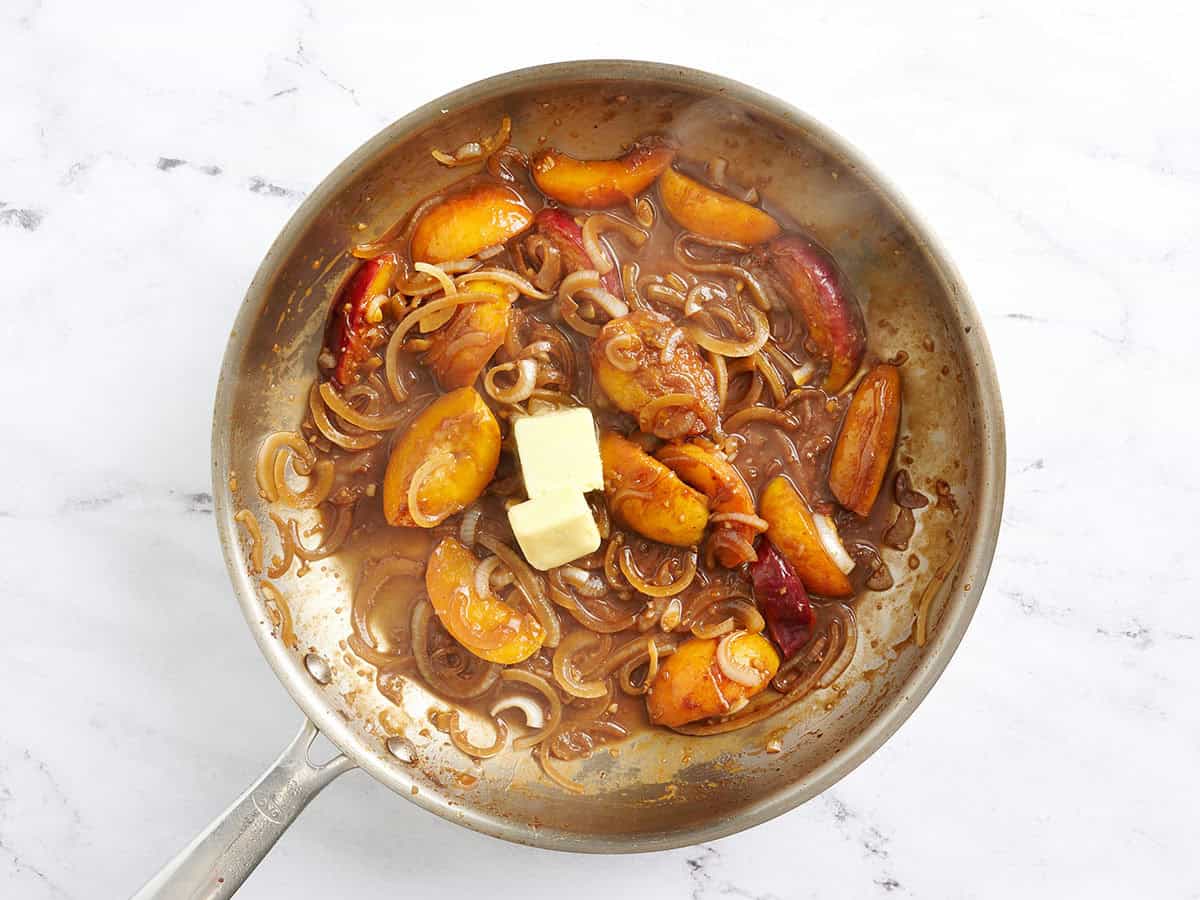 La mantequilla se agregó a una salsa de durazno y cebolla en una sartén.