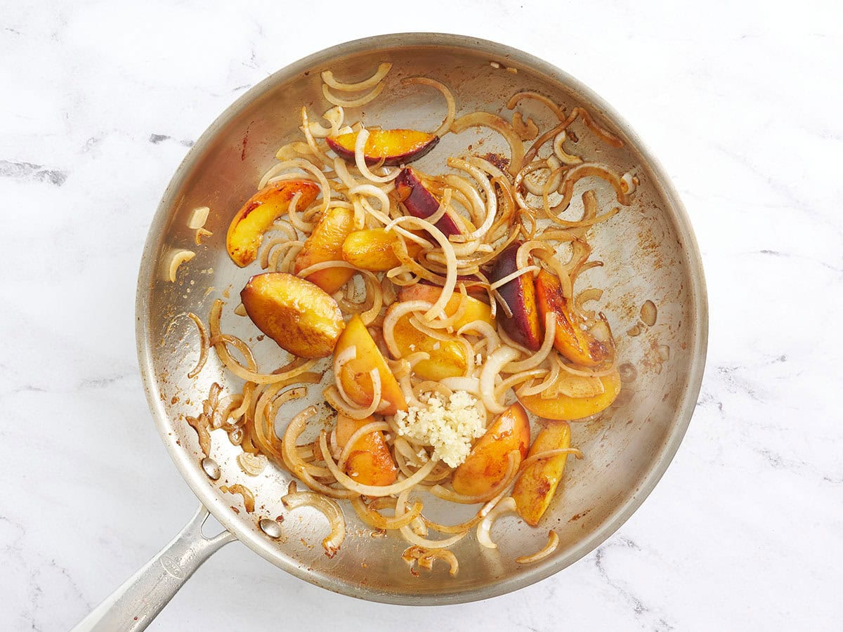 Saltear rodajas de durazno y cebollas en una sartén con ajo picado.