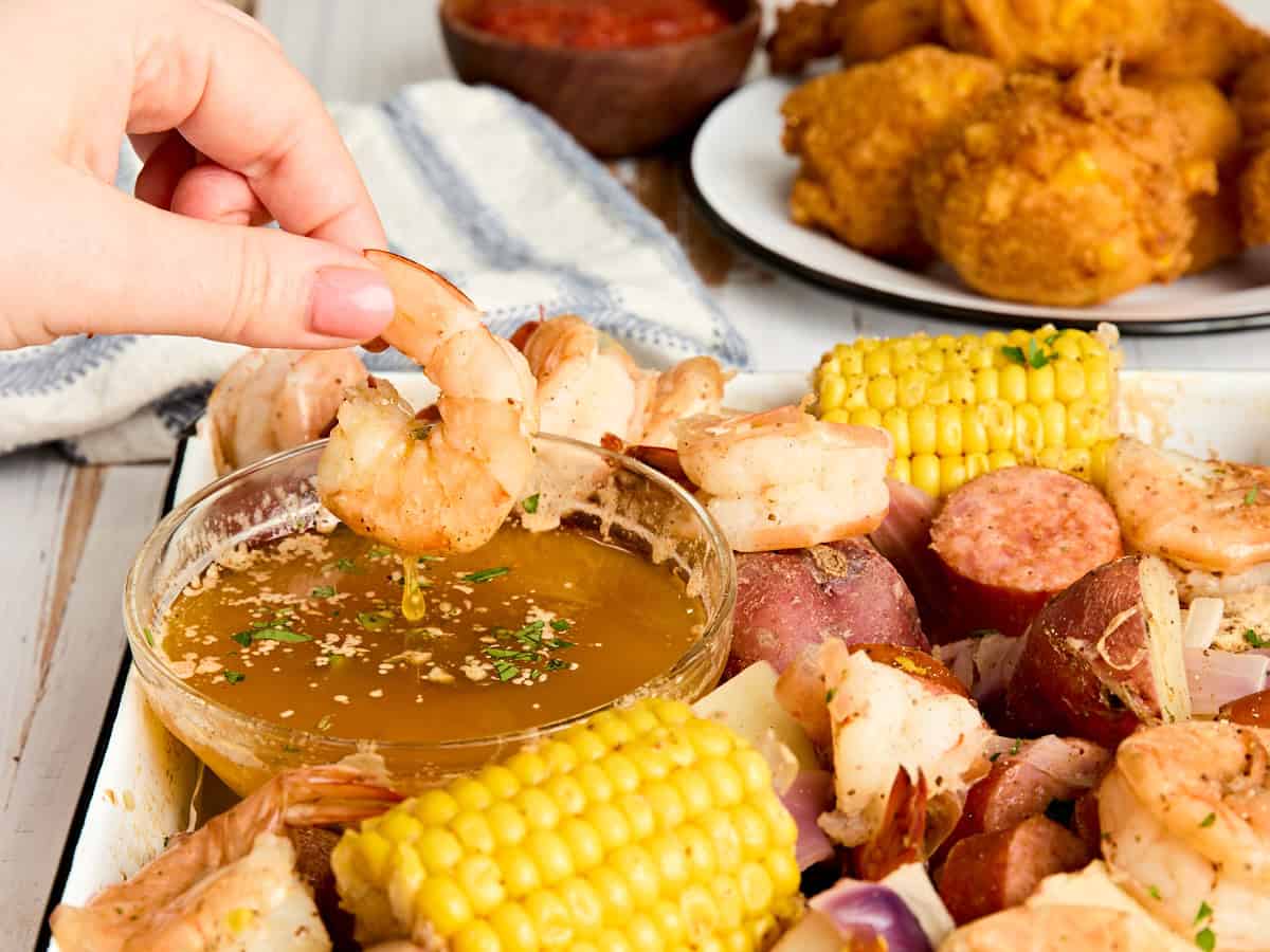 Un trozo de camarones se sumerge en mantequilla sazonada.