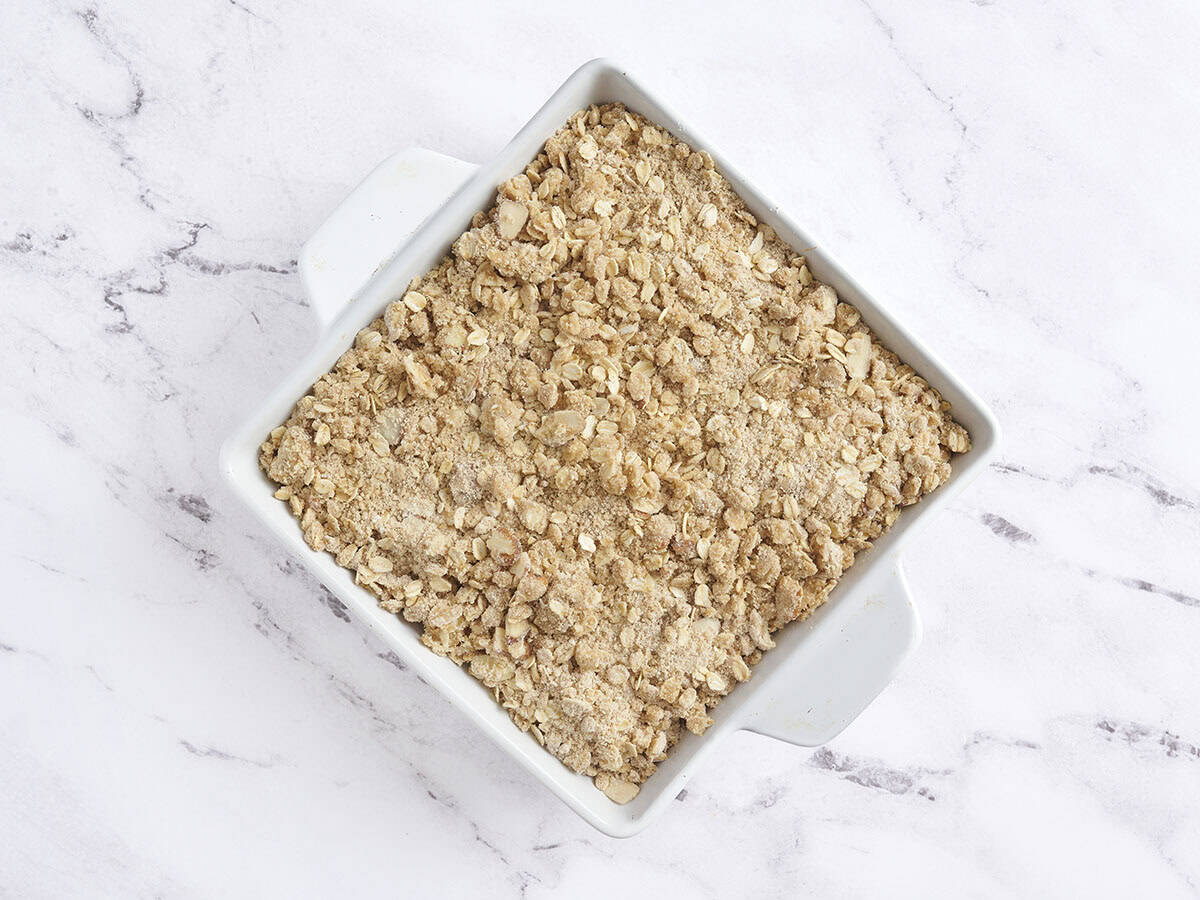 Un durazno ensamblado crujiente en una fuente para hornear antes de hornear.