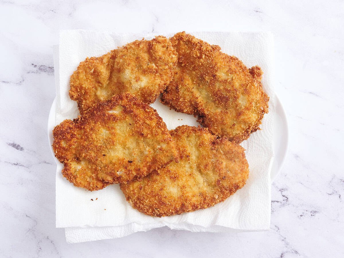 Cuatro esqunitzels de pollo descansando sobre toallas de papel.