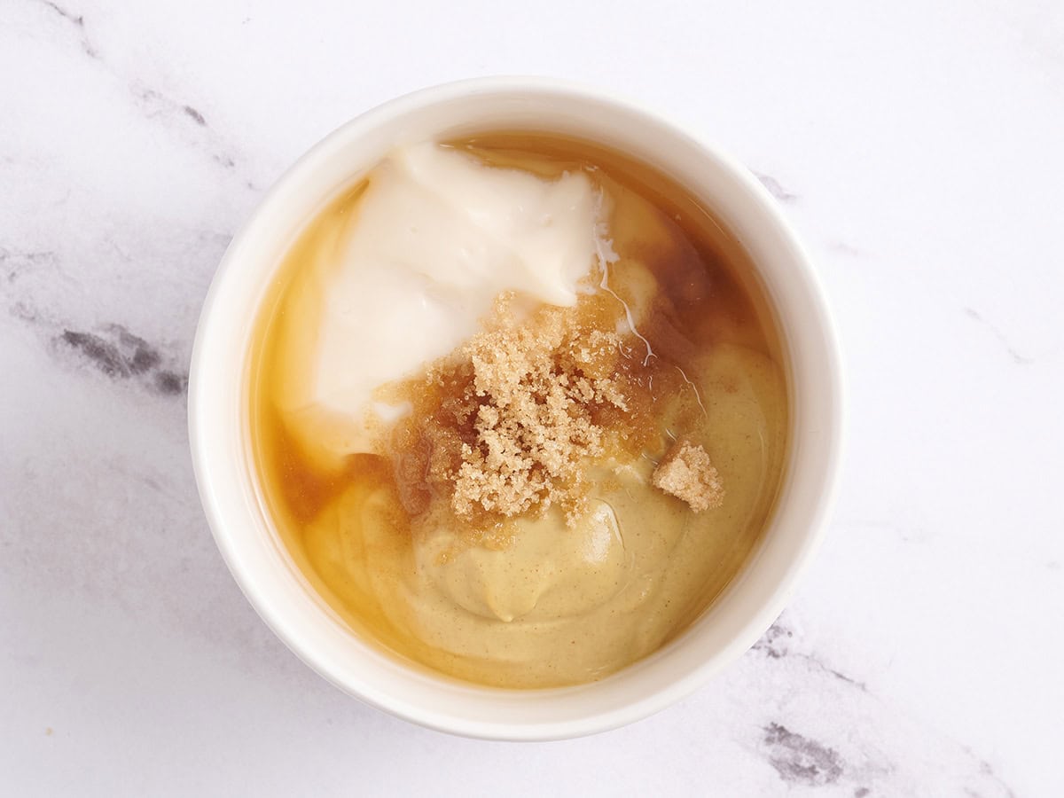 El azúcar morena, la mayonesa, la mostaza y el vinagre de manzana en un tazón para hacer salsa de mostaza.