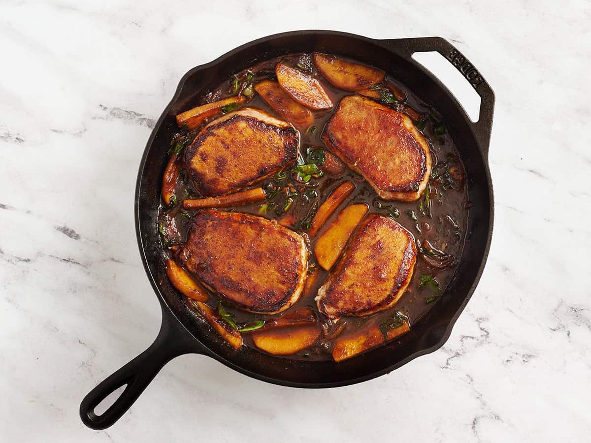 Termadas chuletas de cerdo de mantequilla de manzana en una sartén.