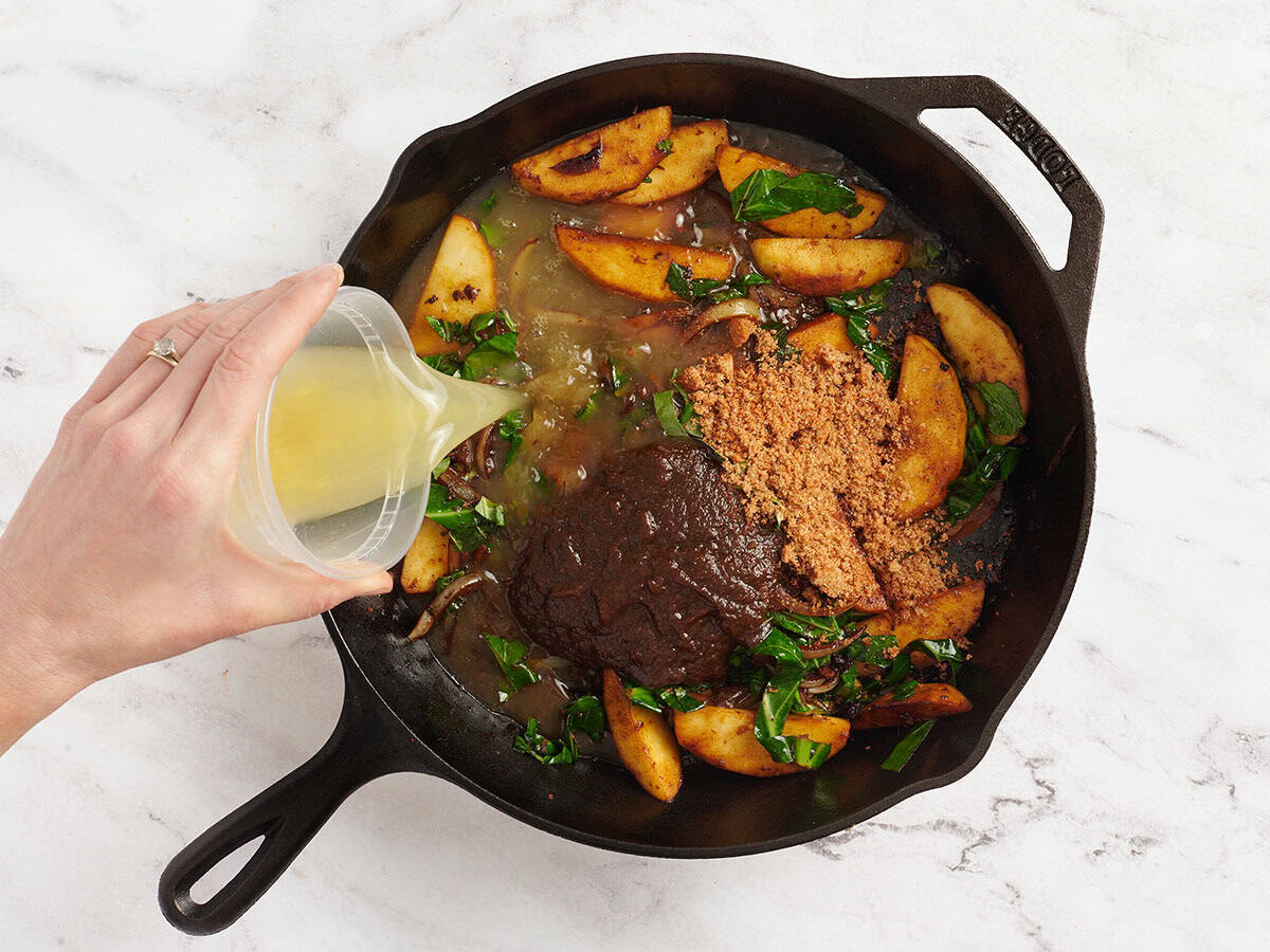 La mantequilla de manzana, el caldo de pollo y los condimentos se agregaron a una sartén con cebollas y colegas verdes.