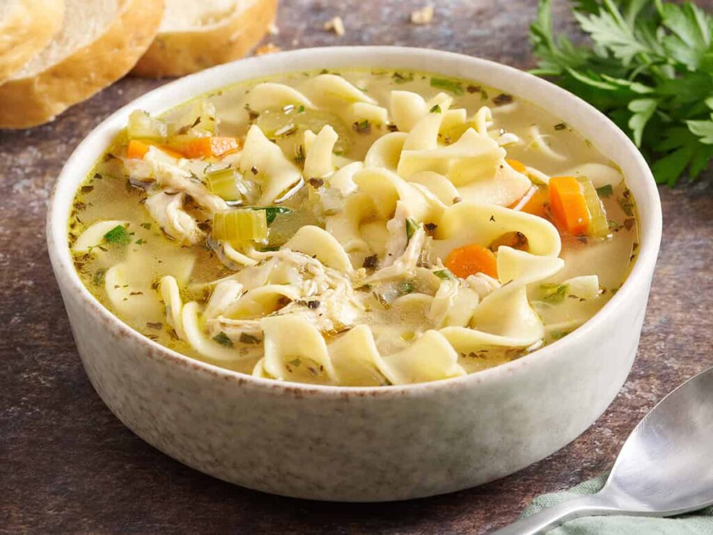 Side view of a bowl of chicken noodle soup.