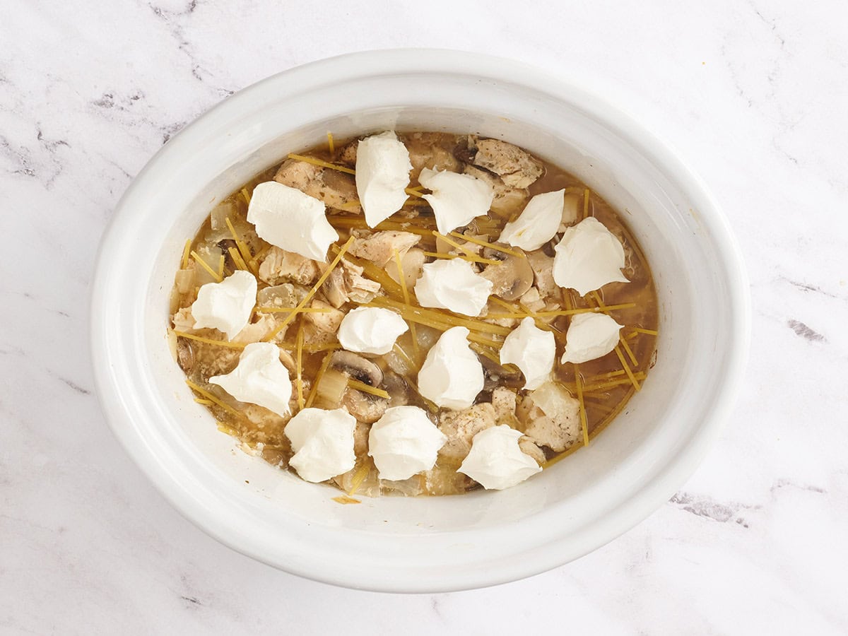 Fideos y queso crema agregado a una olla de tetrazzini de pollo.
