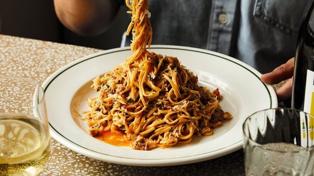 Un hombre tomando un bocado de pasta de un plato.