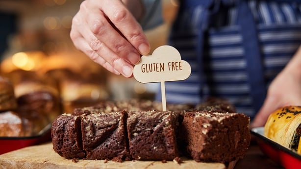 Asistente de ventas en panadería poniendo etiquetas sin gluten en brownies recién horneados