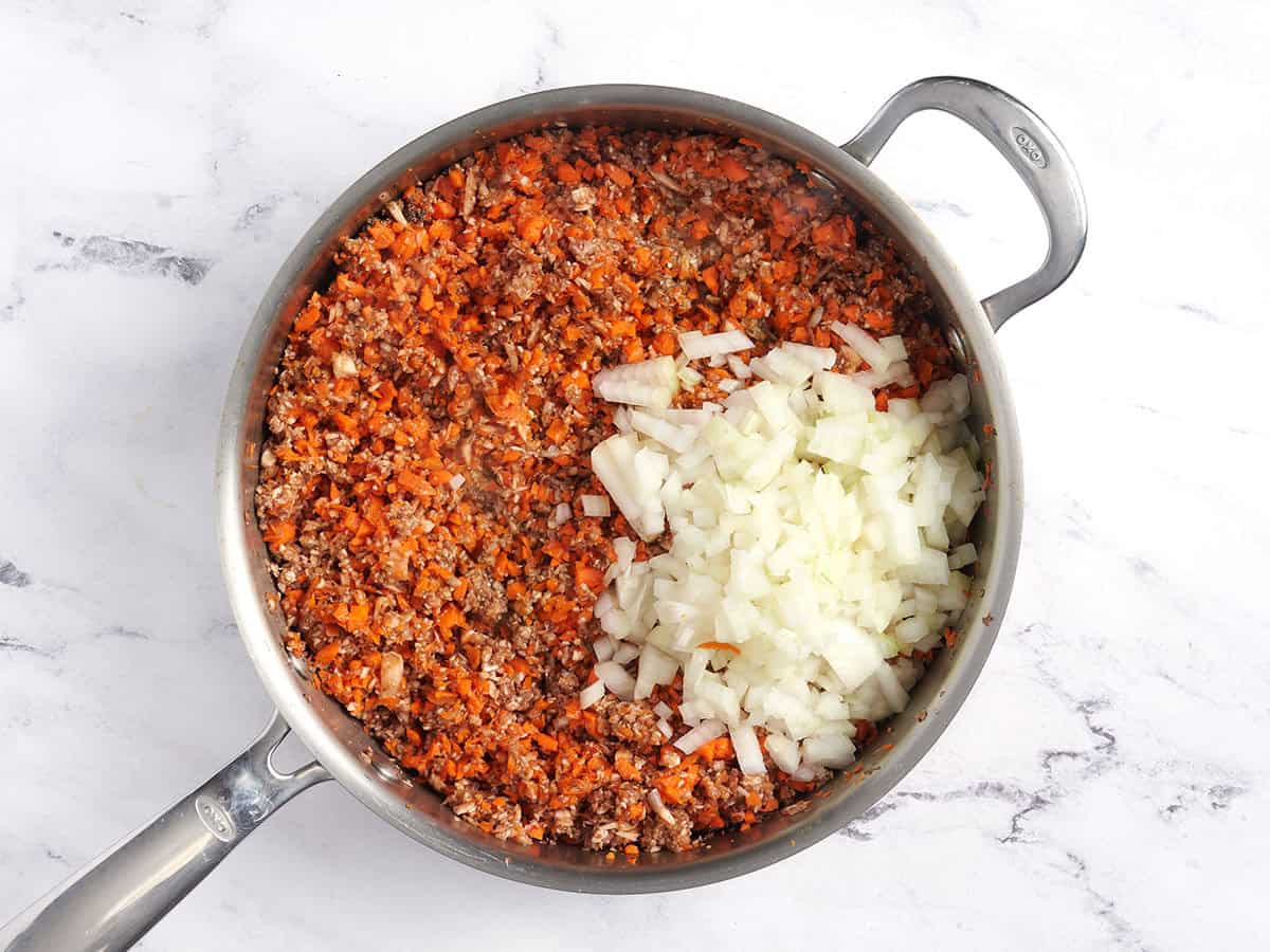 Zanahorias, champiñones y cebolla procesados ​​en una cacerola.