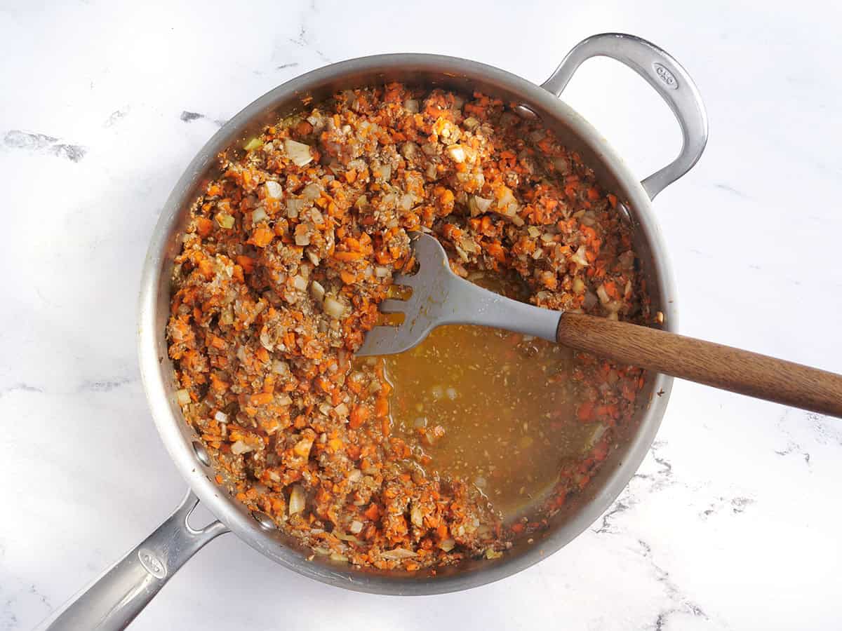 Ingredientes del pastel de carne de lentejas en una sartén con una espátula.