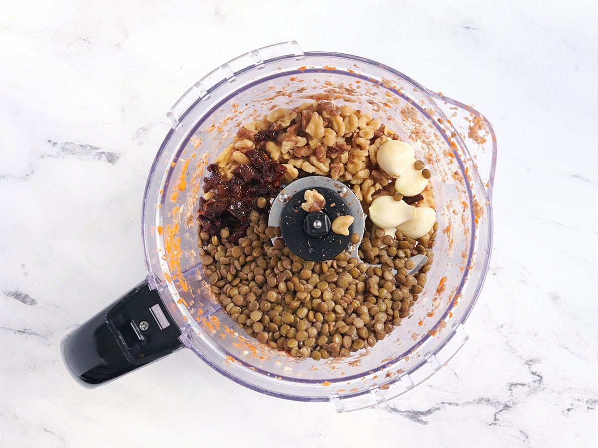 Ajo, lentejas, nueces y tomates secos en un procesador de alimentos.