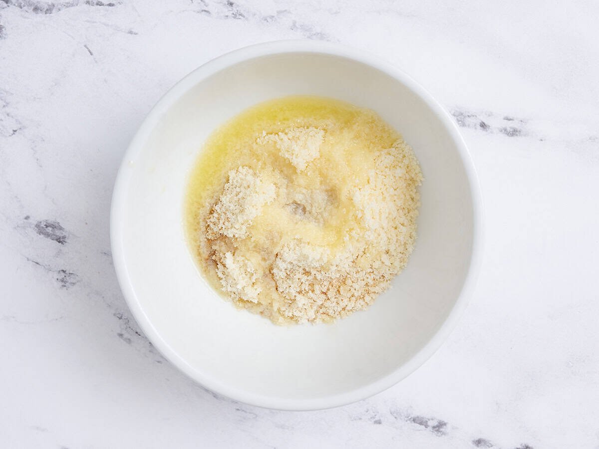 Pan rallado, condimentos y mantequilla derretida en un bol.