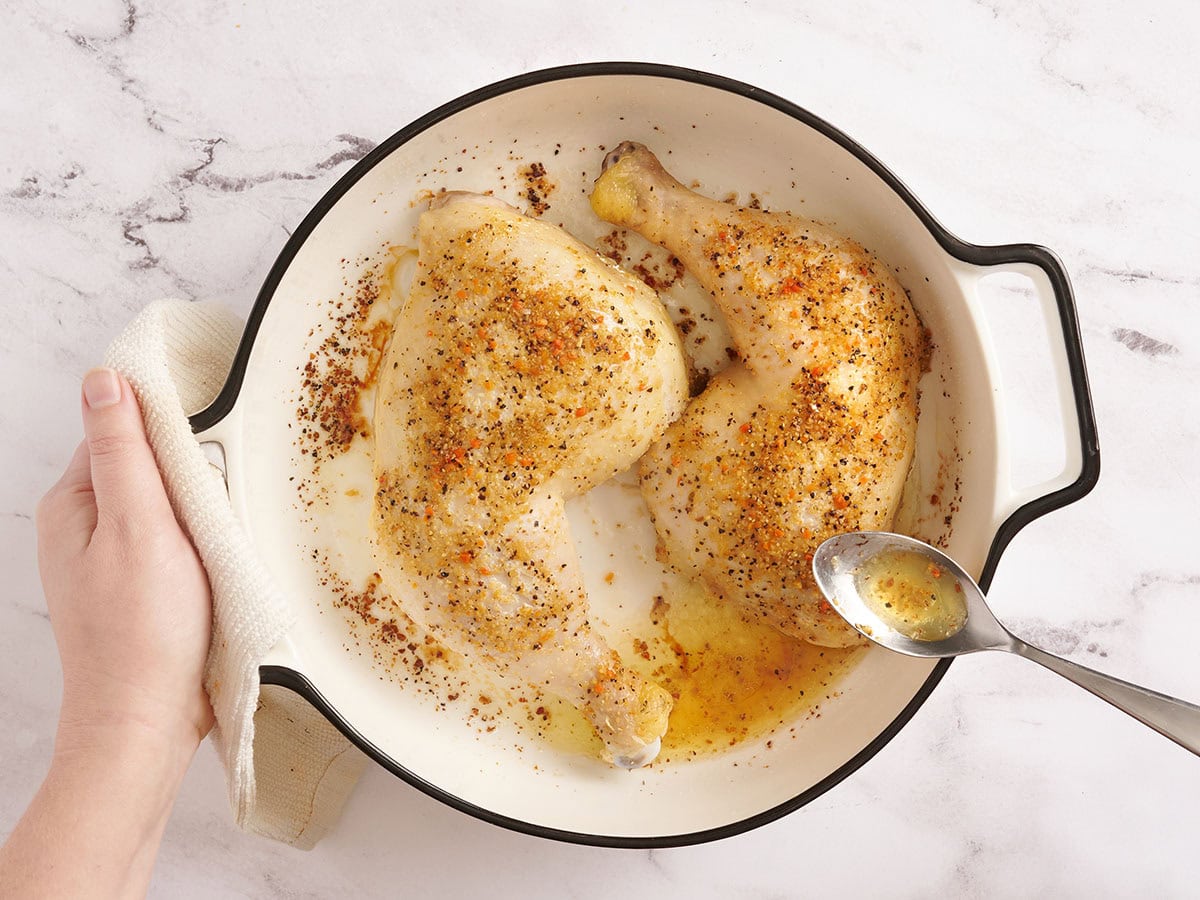 Una cuchara para rociar las piernas de pollo después de una hora de horneado.