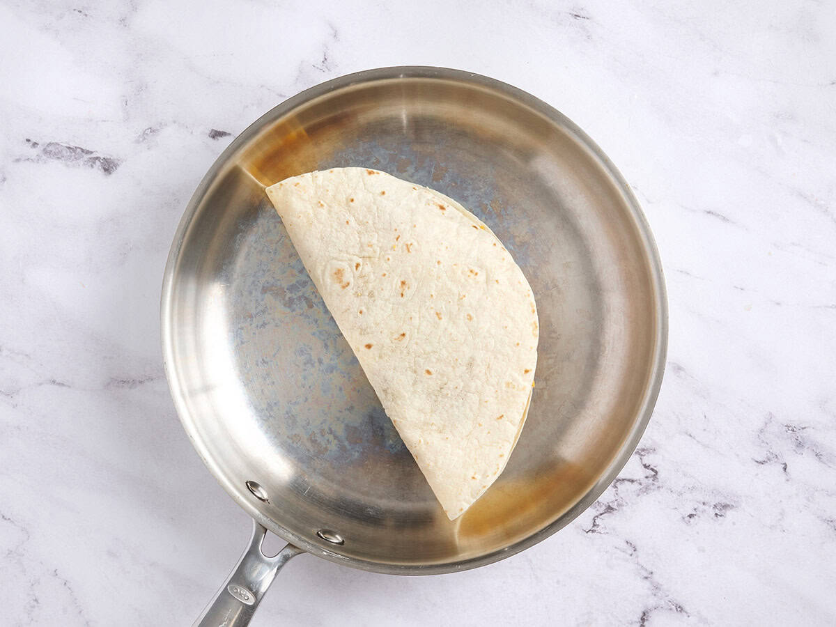 Una tortilla doblada cocinándose en una sartén.