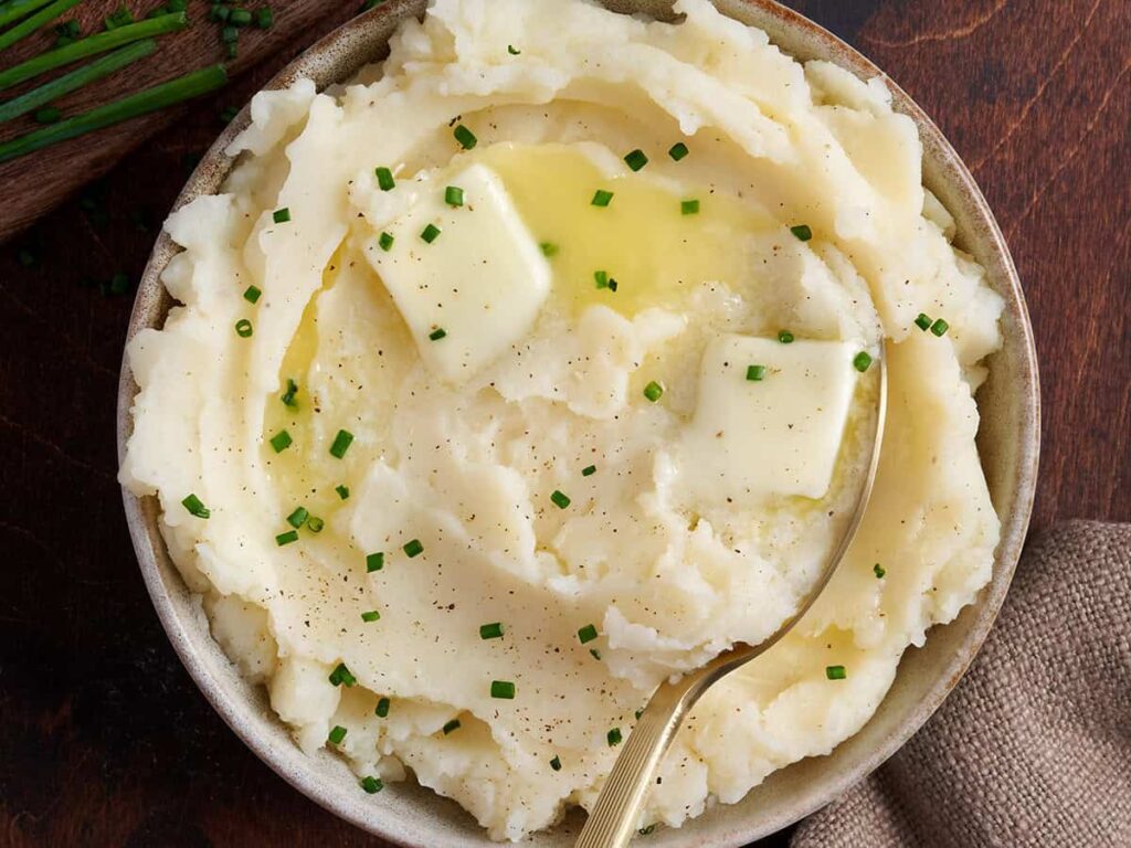Overhead view of buttery instant pot mashed potatoes in a bowl with a spoon.