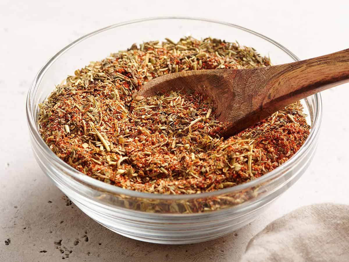 Vista lateral de un plato de condimento para aves con una cuchara de madera.