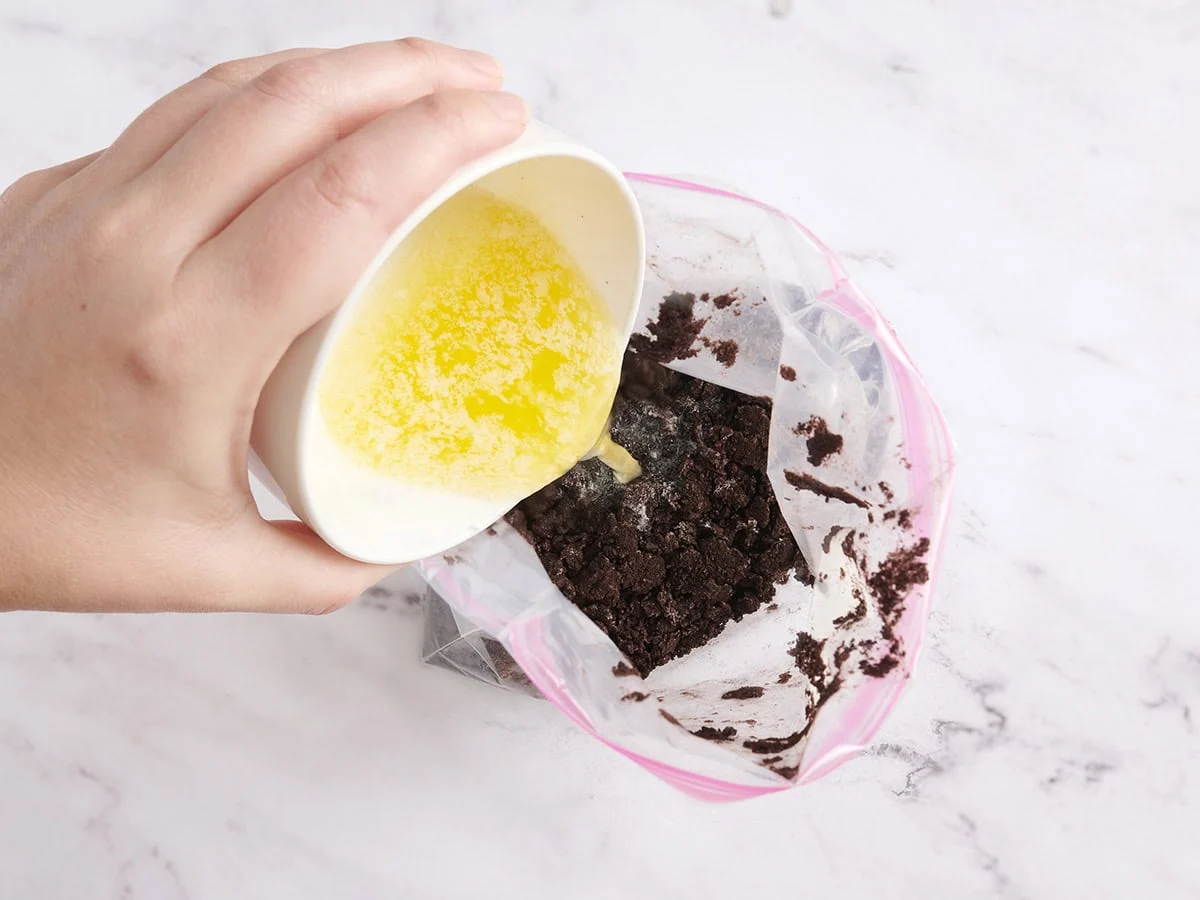 Se vierte mantequilla en una bolsa ziplock de migas de galleta.