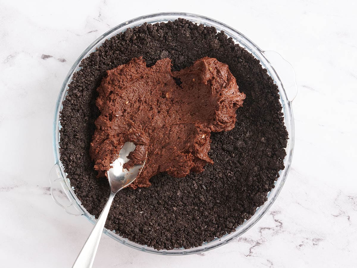 Masa de brownie untada sobre una base de pastel de chocolate.
