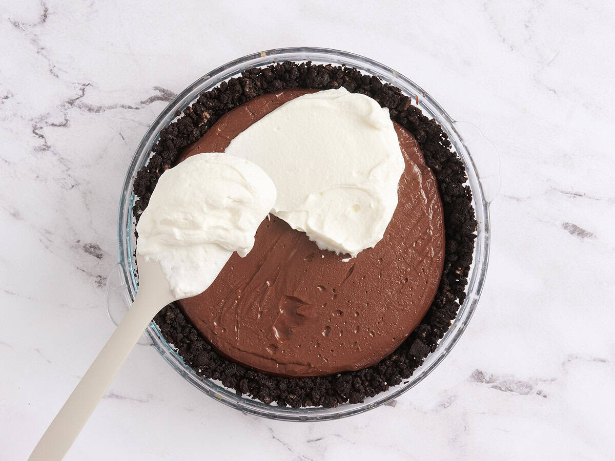 Untar crema batida sobre un pastel de barro de Mississippi.