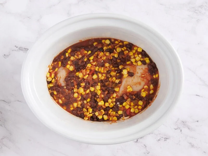 Combinando los ingredientes para tazones de pollo para tacos en la olla eléctrica.