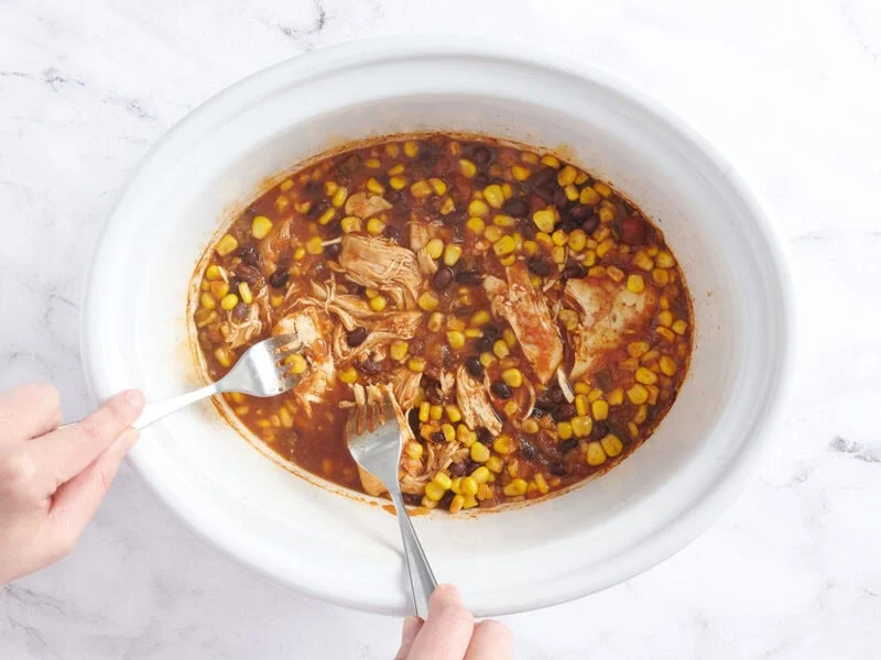 Desmenuzar el pollo en la olla.