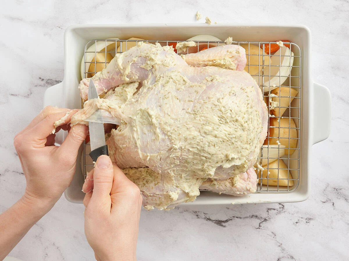 Un cuchillo que perfora la piel de un pollo entero.