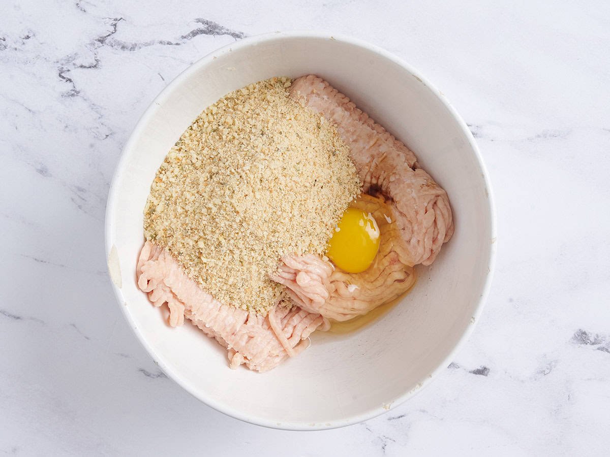 Pollo molido, huevo y pan rallado en un bol.