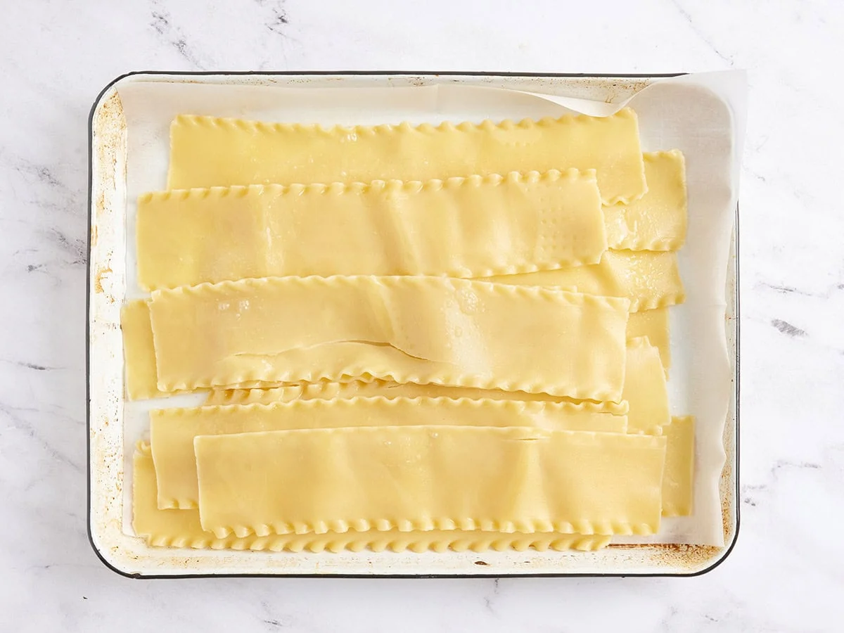 Fideos de lasaña cocidos en una bandeja para hornear.