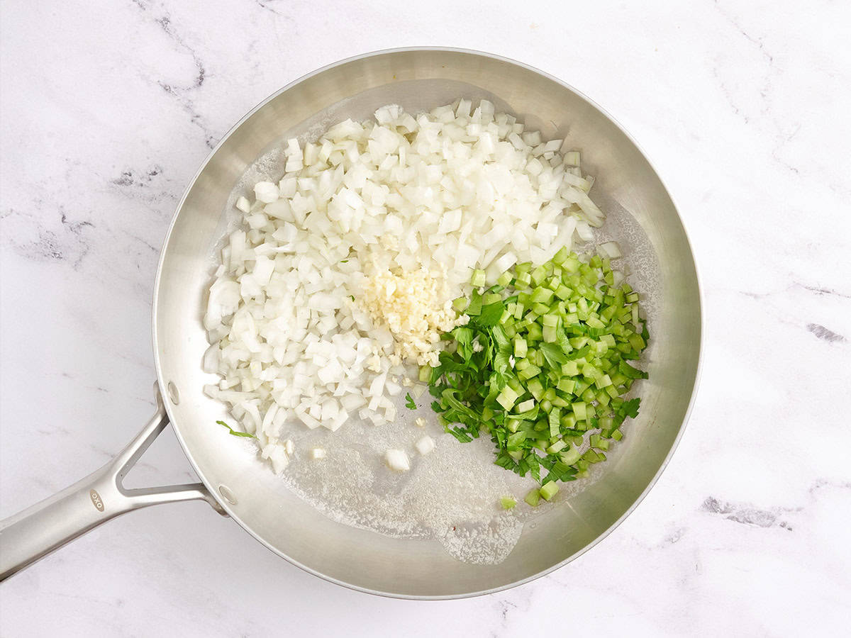 Cebollas, apio, ajo y mantequilla en una sartén.