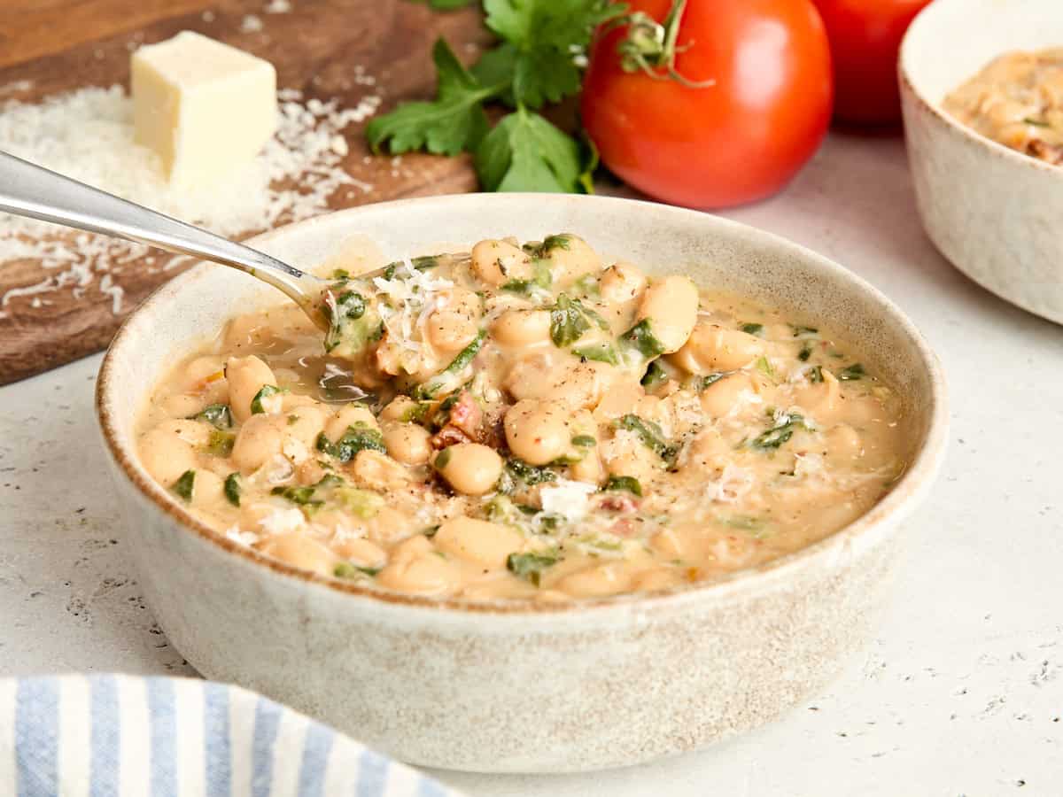 Vista lateral de un plato de cásate conmigo frijoles blancos con una cuchara.