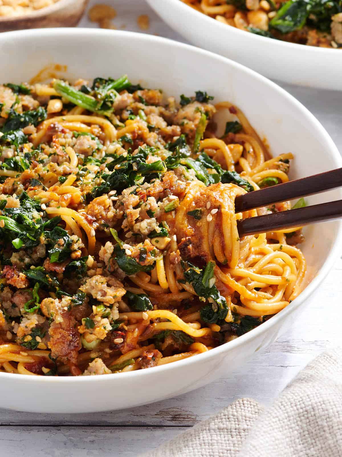 Vista lateral de un plato de fideos dan dan con palillos. Vista aérea de un plato de fideos dan dan con palillos.