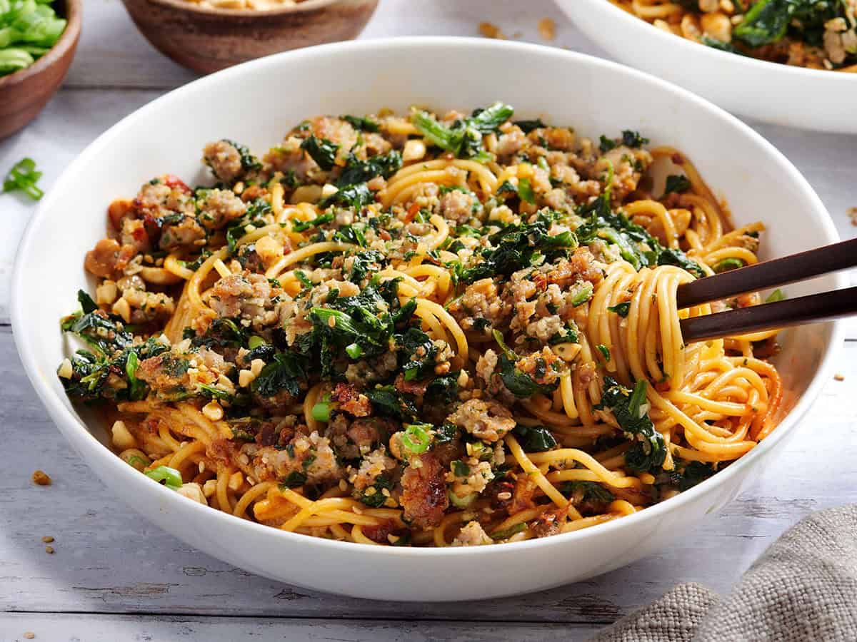 Vista lateral de un plato de fideos dan dan con palillos. Vista aérea de un plato de fideos dan dan con palillos.