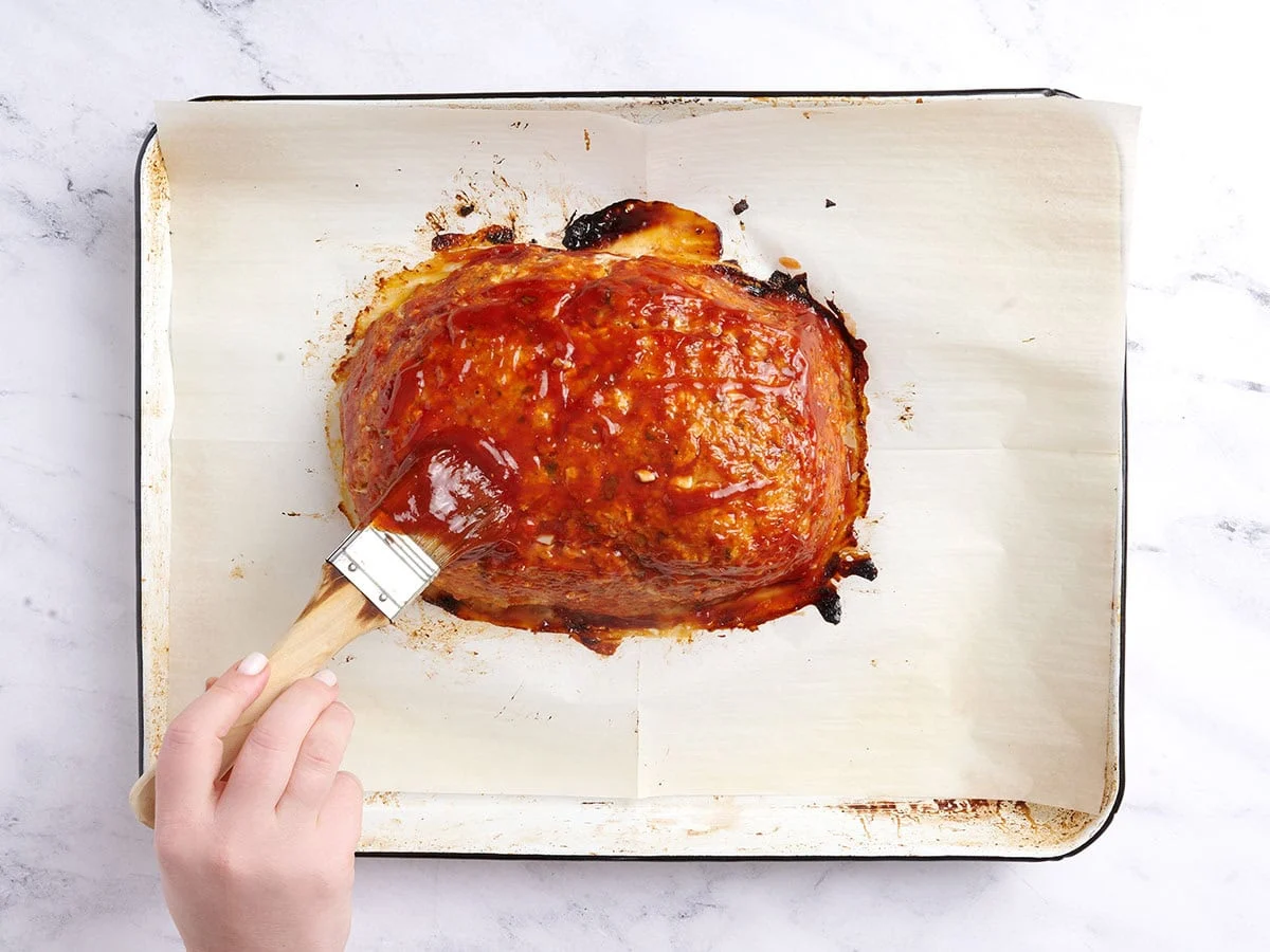 Untar el pastel de carne con glaseado después de 40 minutos de horneado. 