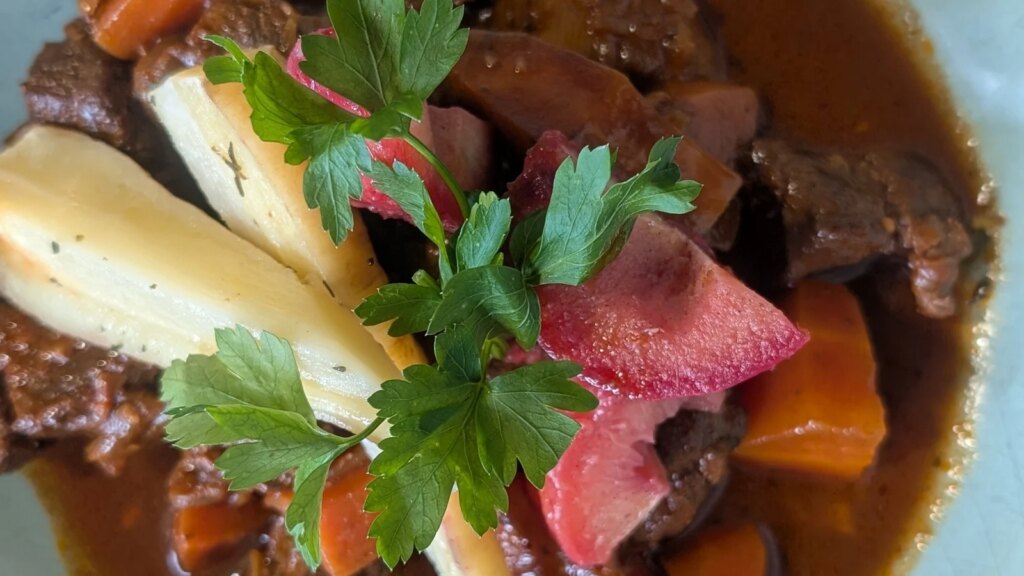 Estofado de ternera cocido a fuego lento de Alex Petit con ciruelas y chirivías escalfadas en vino tinto