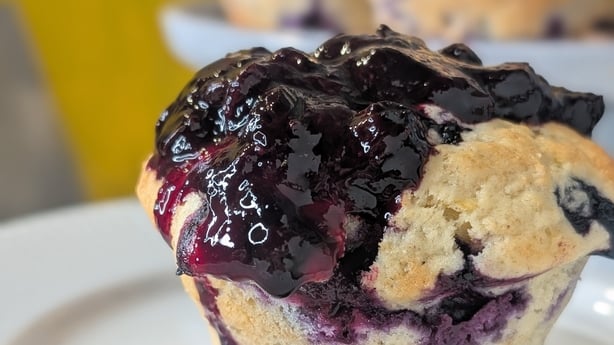 Un muffin de limón y arándanos cubierto con salsa de arándanos