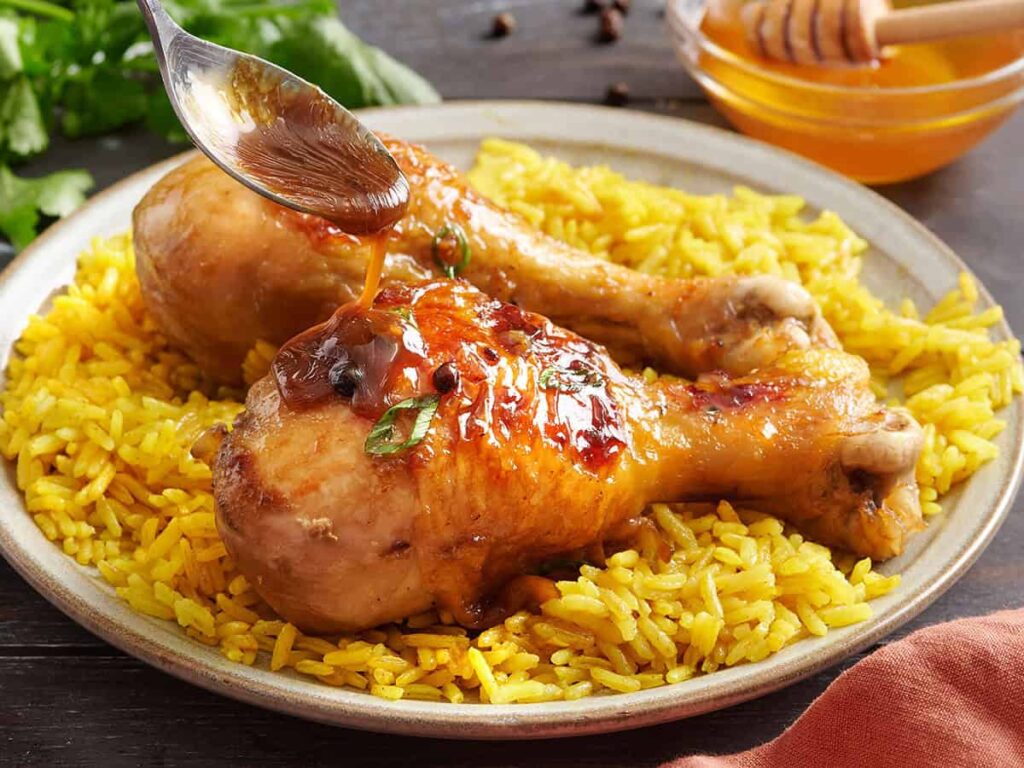 Side view of chicken adobo on a plate with yellow rice.