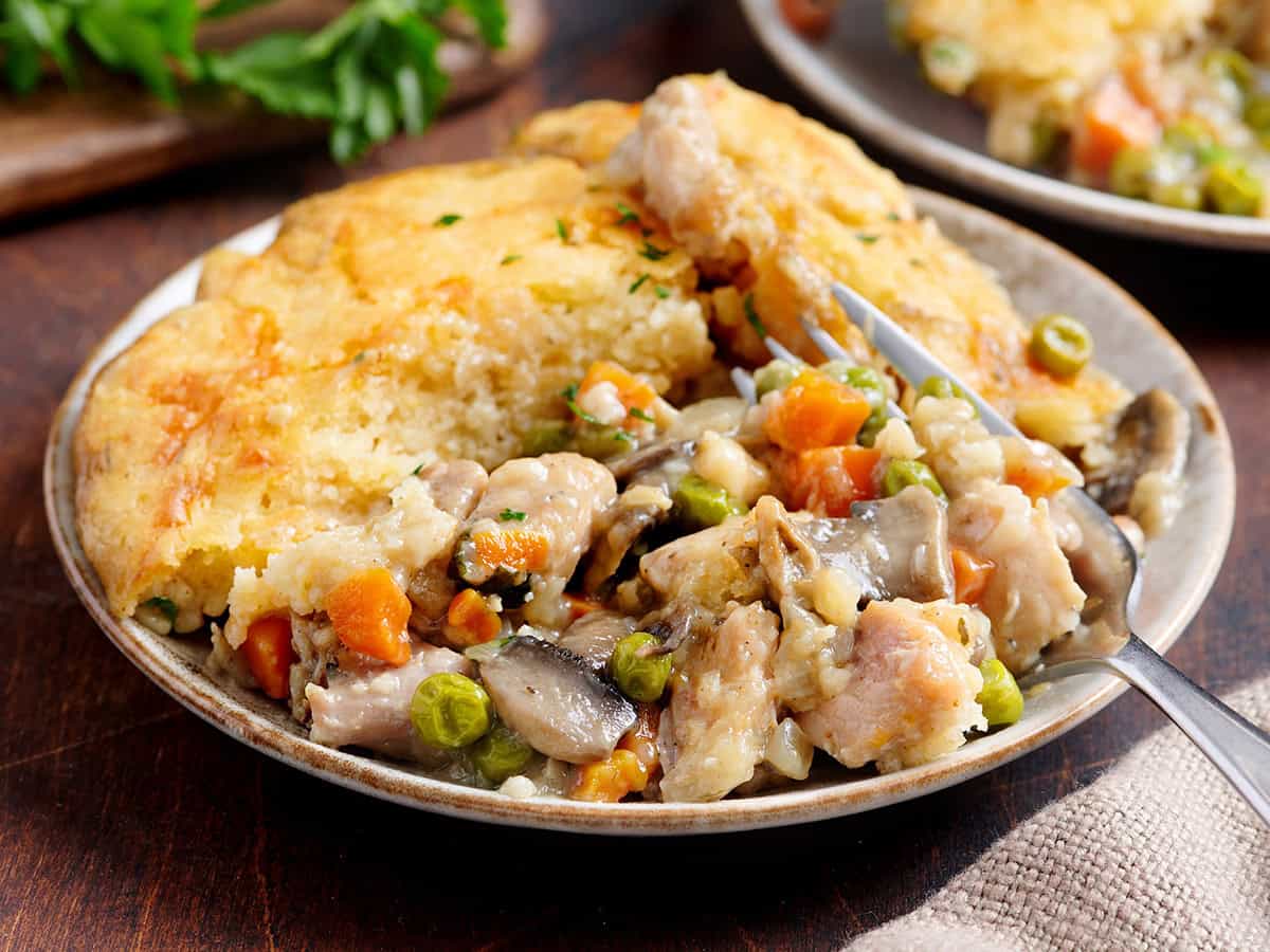 Vista lateral del pastel de pollo en un plato con un tenedor.