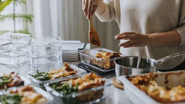 Mujer pesando loncheras como parte de la preparación de comidas saludables