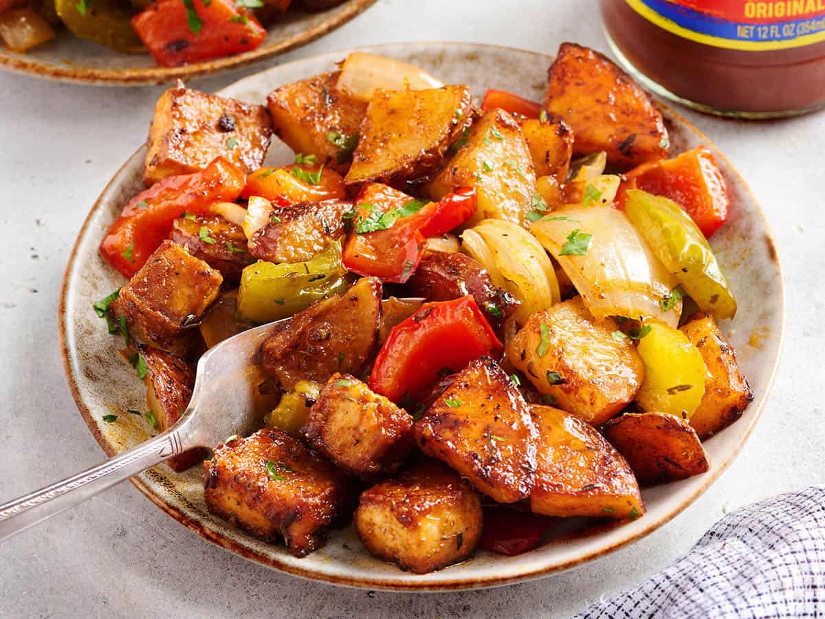 Un plato de hoja Pan Cajun Tofu y verduras con un tenedor.