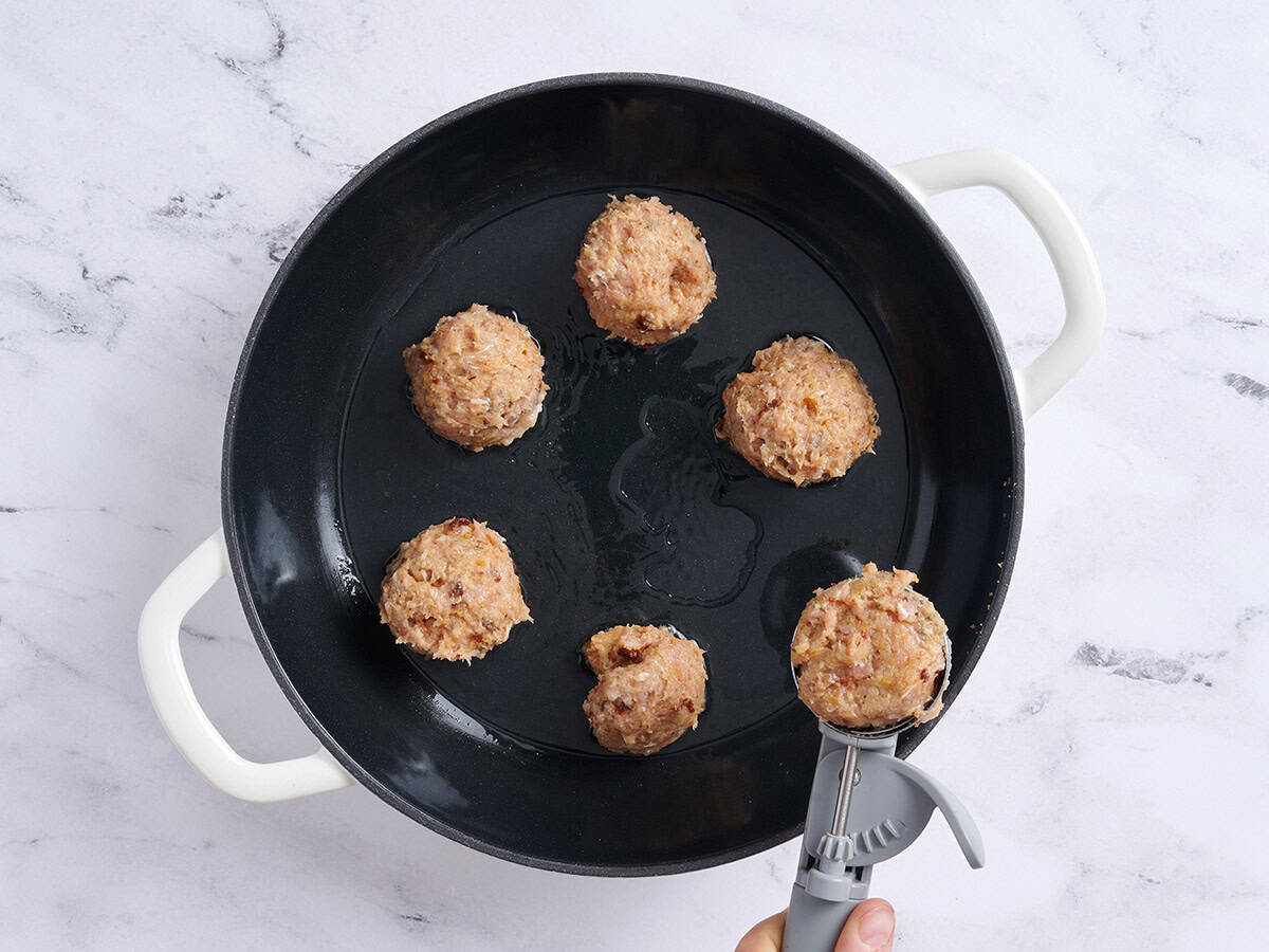 Una bola de helado añadiendo albóndigas a una sartén.