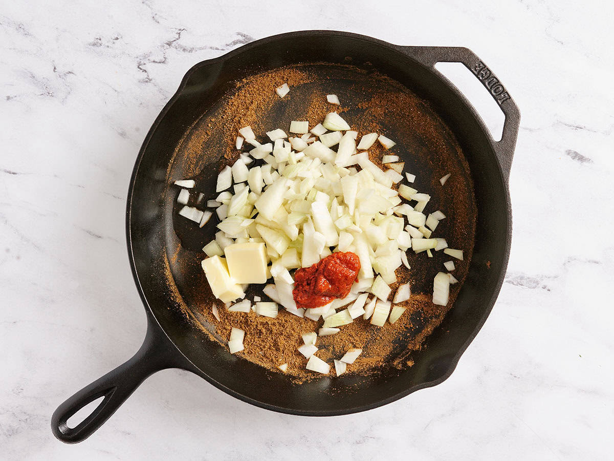 Cebolla picada en una sartén con pasta de curry rojo.