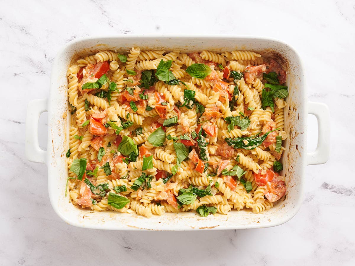 Pasta feta horneada terminada en una fuente para horno cubierta con albahaca.