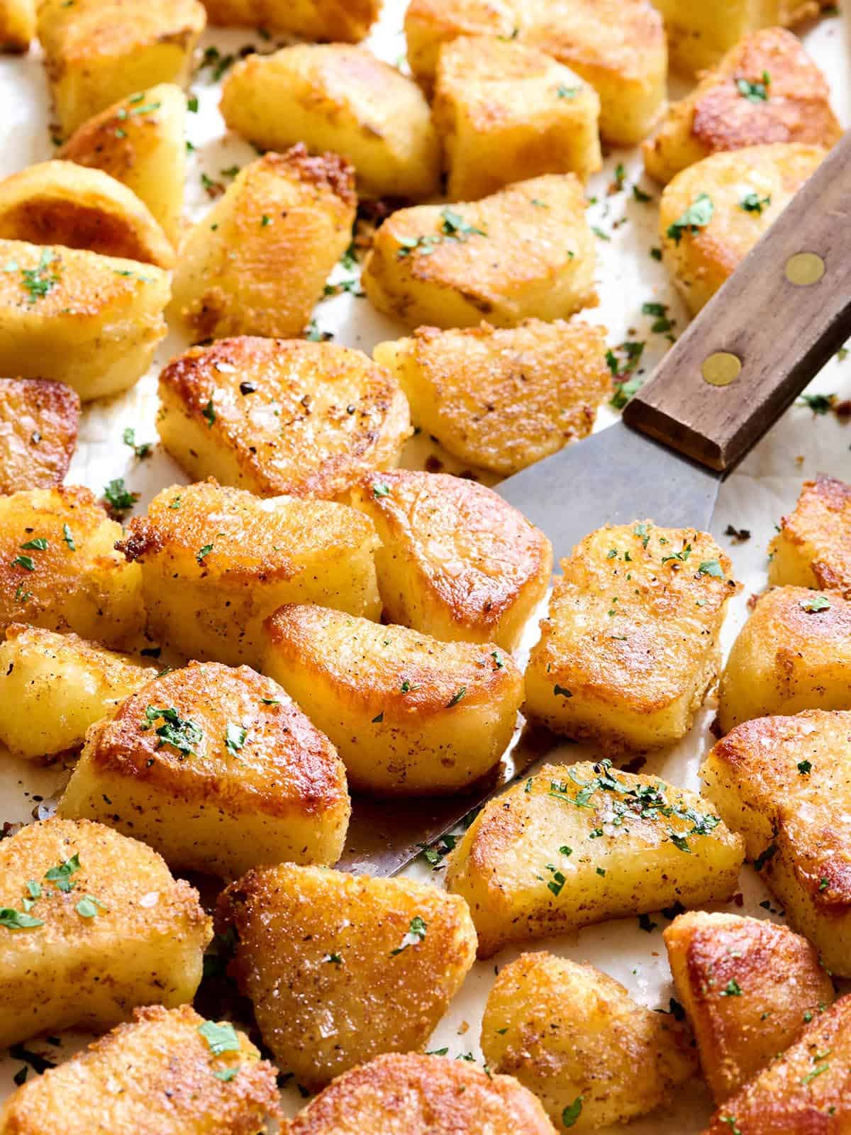 Patatas asadas al horno en una bandeja para horno con una espátula.