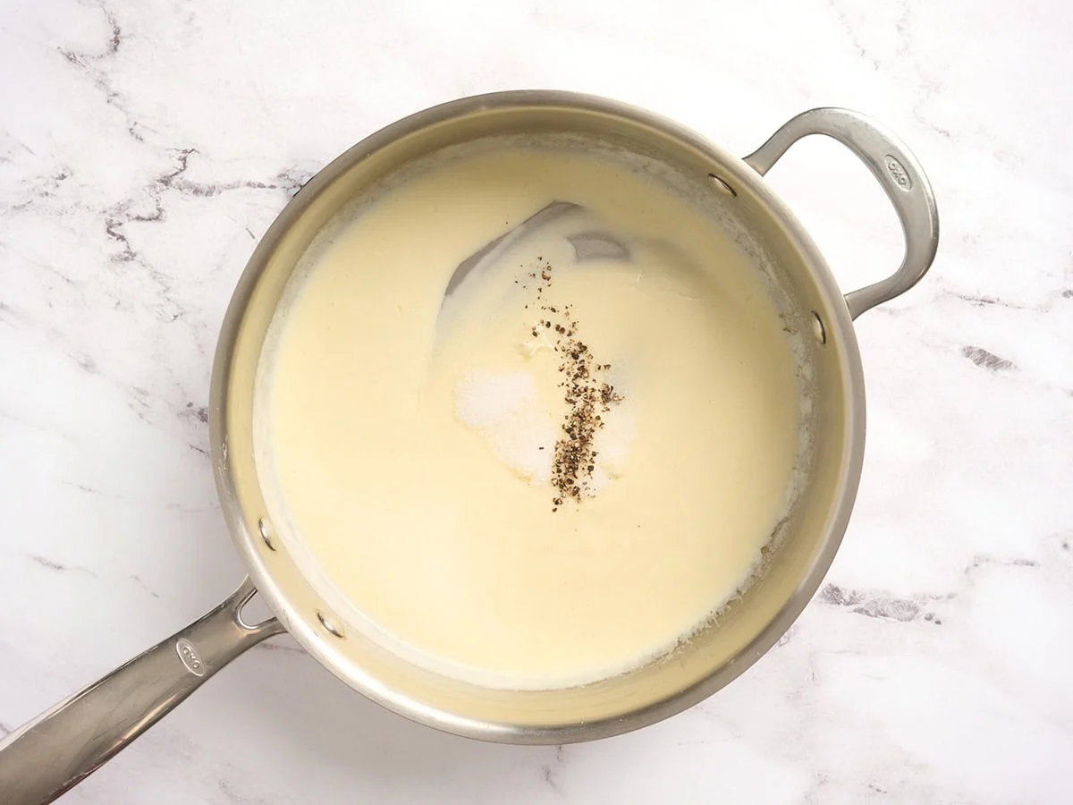 Una salsa de crema en una sartén con condimentos añadidos.