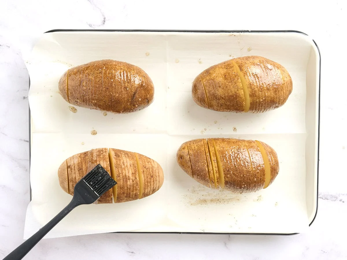 Patatas Hasselback untadas con aceite sazonado.